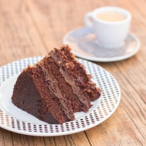 Delicious slice of chocolate cake served with coffee on a rustic wooden table, perfect for dessert lovers.
