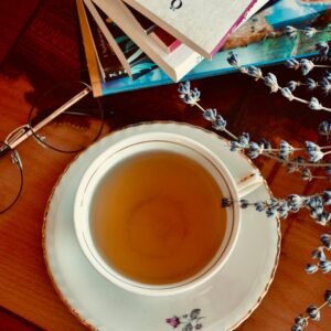 A warm tea cup surrounded by books and eyeglasses, creating a cozy atmosphere.