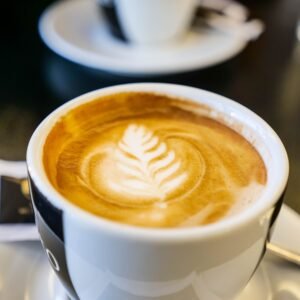 Aesthetic close-up of a cappuccino cup showcasing intricate latte art on a table.
