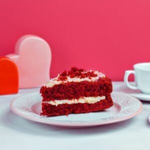 A vibrant still life featuring red velvet cake and a doughnut on a table with heart decorations.