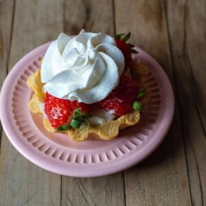 Delicious strawberry tart topped with whipped cream, served on a pink plate. Perfect for dessert lovers.